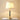Gouden tafellamp met witte lampenkap op witte tafel, moderne verlichting, interieurdecoratie.