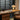 Bureaulamp op houten bureau met leren stoel en jaloezieën, moderne interieurverlichting.
