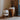 Cesta tafellamp wit glas en hout, modern design, naast houten bijzettafel met boeken en plant.