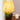 Groene glazen tafellamp met geel patroon lampenkap op houten tafel naast witte kaars.