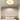 Moderne witte plafondlamp in bloemvorm boven een minimalistische slaapkamer.