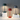 Drie moderne tafellampen, groen, rood en grijs, minimalistisch design, op witte blokken.