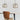 Twee glazen hanglampen boven houten tafel en leren stoel, modern interieurontwerp.