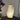 Moderne witte tafellamp met golvend ontwerp, sfeerverlichting, naast paarse bloemen in vaas.