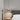 Moderne zwarte hanglamp boven houten nachtkastje in minimalistische slaapkamer.