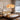 Houten bed met rotan hoofdeinde, hanglamp met bloemvormige kap, moderne slaapkamerinrichting.