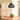 Zwarte rotan hanglamp boven houten eettafel met planten, modern interieurontwerp.