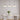 Drie witte hanglampen boven moderne eettafel met bloemenvaas, minimalistisch interieurontwerp.