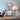 Chromen tafellamp met halve bol, moderne verlichting, naast bloemen en blauwe kunstprint.
