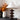 Houten torenlamp met witte kap op kast, naast vaas met herfstbladeren, moderne interieurdecoratie.