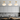 Drie moderne plafondlampen goud en wit glas boven minimalistische keuken.