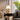 Gouden koloniale vloerlamp op houten tafel, klassieke stijl, naast grijze fauteuil en plant.