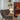 Grijze fauteuil en tafellamp met glazen kap in moderne woonkamer, houten vloer.