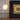 Gouden tafellamp met ronde witte bol op houten tafel naast geometrisch kunstwerk.