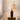 Donkere keramische tafellamp met beige lampenkap op houten tafel, moderne interieurverlichting.