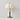 Witte stoffen tafellamp met houten voet en messing details, elegante bloemenprint.