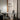 Moderne glazen hanglamp boven zwarte tafel in minimalistisch interieur met laptop en stoel.