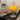 Gele Quadrifoglio tafellamp op zwarte tafel naast vintage platenspeler en stapel cd's.