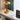 Moderne messing tafellamp met glazen kap op houten bureau naast laptop en tijdschrift.