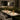 Moderne restaurantinterieur met marmeren tafels, groene banken en koperen tafellampen.