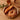 Ronde rieten mand met stokbrood en krakeling, houten tafel, bloemen, glas thee.
