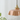 Roze keramische hanglamp met vintage messing fitting, decoratieve verlichting, planten op achtergrond.