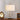 Messing tafellamp met witte lampenkap en decoratieve takken, elegante verlichting.