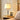 Gouden tafellamp met witte lampenkap op houten nachtkastje, moderne slaapkamerverlichting.