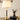 Gouden tafellamp met witte kap op houten tafel naast hertensculptuur, moderne interieurdecoratie.