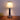 Chromen tafellamp met witte lampenkap, houten tafel, moderne verlichting, interieurdecoratie.