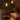 Twee zwarte LED-tafellampen op houten tafel naast boek en kaars.