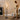 Vrouw in beige jurk bedient moderne zwarte vloerlamp met drie LED-buizen in woonkamer.
