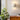 Wandlamp modern wit keramiek, naast houten kast en groene kamerplant, interieurdecoratie.
