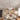 Moderne woonkamer met witte kroonluchter, beige bank, decoratieve kunst en planten.