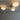 Moderne plafondlamp met drie ronde, witte glazen kappen en goudkleurige armatuur.
