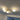 Moderne plafondlamp met vier ronde, witte glazen lampenkappen en goudkleurige armatuur.