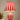 Rood-witte gestreepte tafellamp, circusstijl, decoratief, naast plant en boeken.
