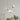 Drie hanglampen in pastelkleuren boven een minimalistisch interieur met planten.