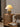 Geribbelde keramische tafellamp met beige kap op rotan kast, sfeerverlichting woonkamer.