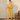 Jonge man in gele badjas van fleece met ceintuur, staand naast bruine leren stoel.