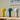Drie moderne tafellampen, geel, blauw en grijs, op houten tafel, minimalistisch design.