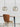 Twee glazen hanglampen boven houten tafel en leren stoel, modern interieurontwerp.