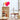 Witte kast met decor, roze hartklok, glazen tafellamp, modern interieur, Scandinavisch design.