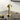 Gouden draadloze LED tafellamp, modern design, op zwart bureau naast glazen beker.
