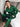 Man in groene satijnen pyjama zittend op bed, luxe nachtkleding, comfortabele slaapkleding.