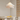 Witte hanglamp in moderne eetkamer met houten details en citroenen op tafel.