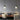 Twee moderne hanglampen boven houten tafel in minimalistisch interieur, grijze muren, kussens.