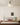 Witte plafondlamp in moderne slaapkamer, houten bed, beige muurdecoratie.