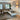 Moderne beige hoekbank in stijlvolle woonkamer met grijze vloerkleed en decoratieve kussens.