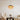 Moderne hanglamp met glazen kap, beige fauteuil, en bloemenvaas in minimalistisch interieur.